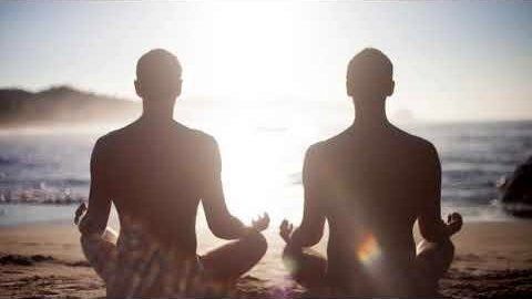 Photo of two men meditating on a beach