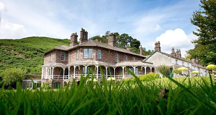 The building at High Close showing the veranda, with a green hillside behind the house and grass in the foreground.