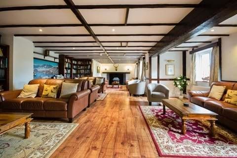 A large room with timbered ceiling and a wooden floor. Sofas and low tables line the walls on either side
