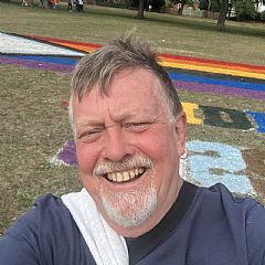 Photo of Steve with a rainbow flag behind