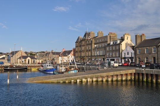 Kirkwall harbour showing a slipway into the sea with buildings behind and a blue sky