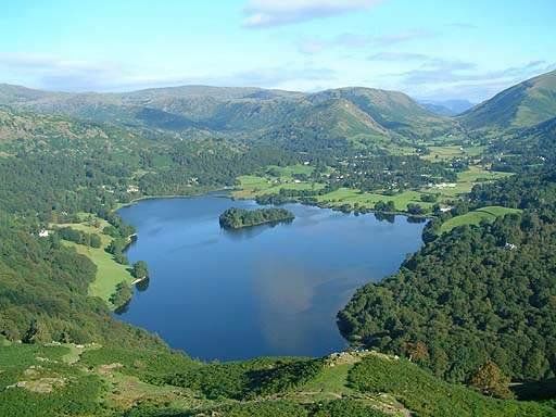 An aerial view of Grasmere lake with hills and blue sky beyond